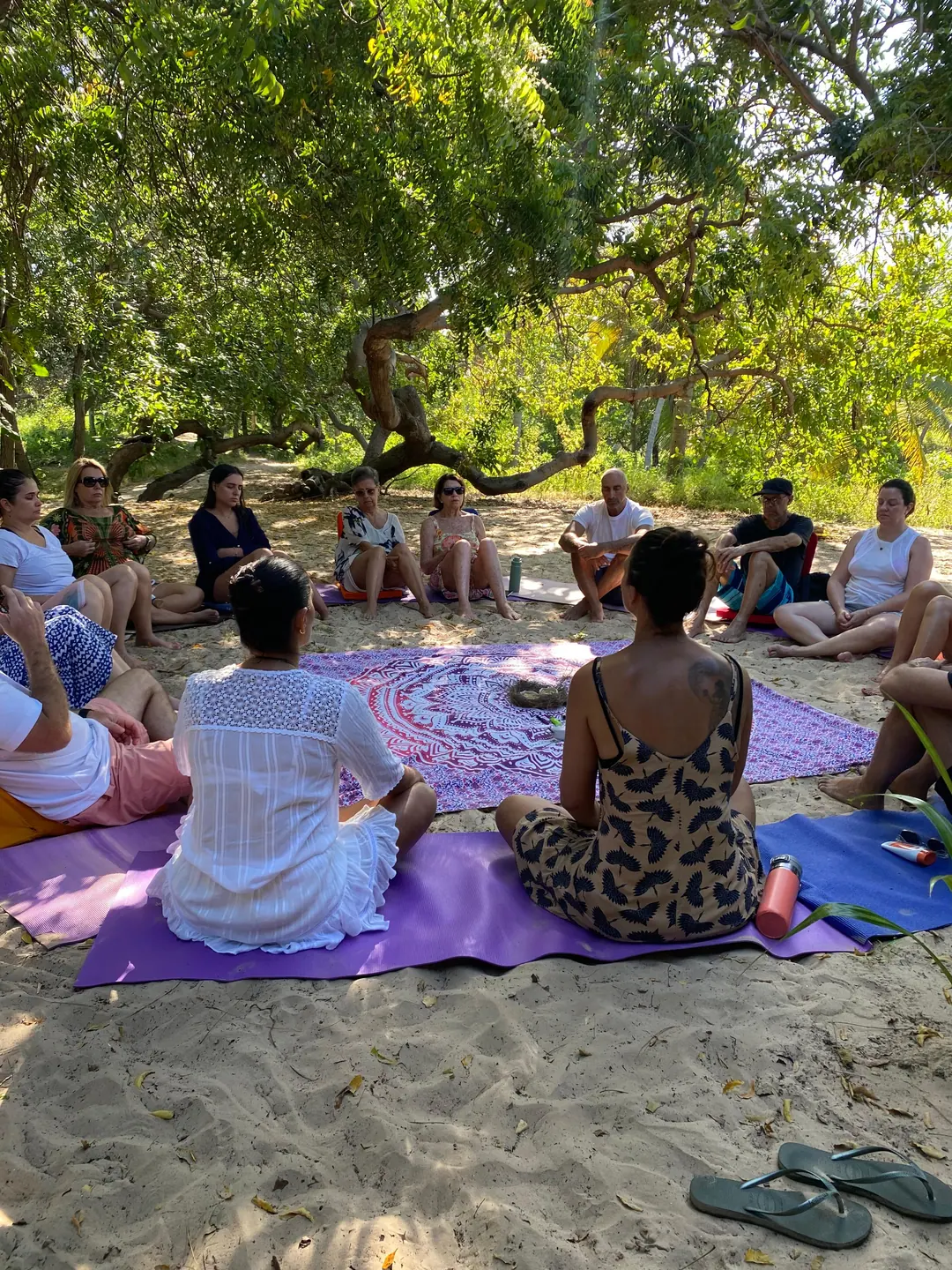Turma sentada na areia, à sombra, num momento de bem-estar