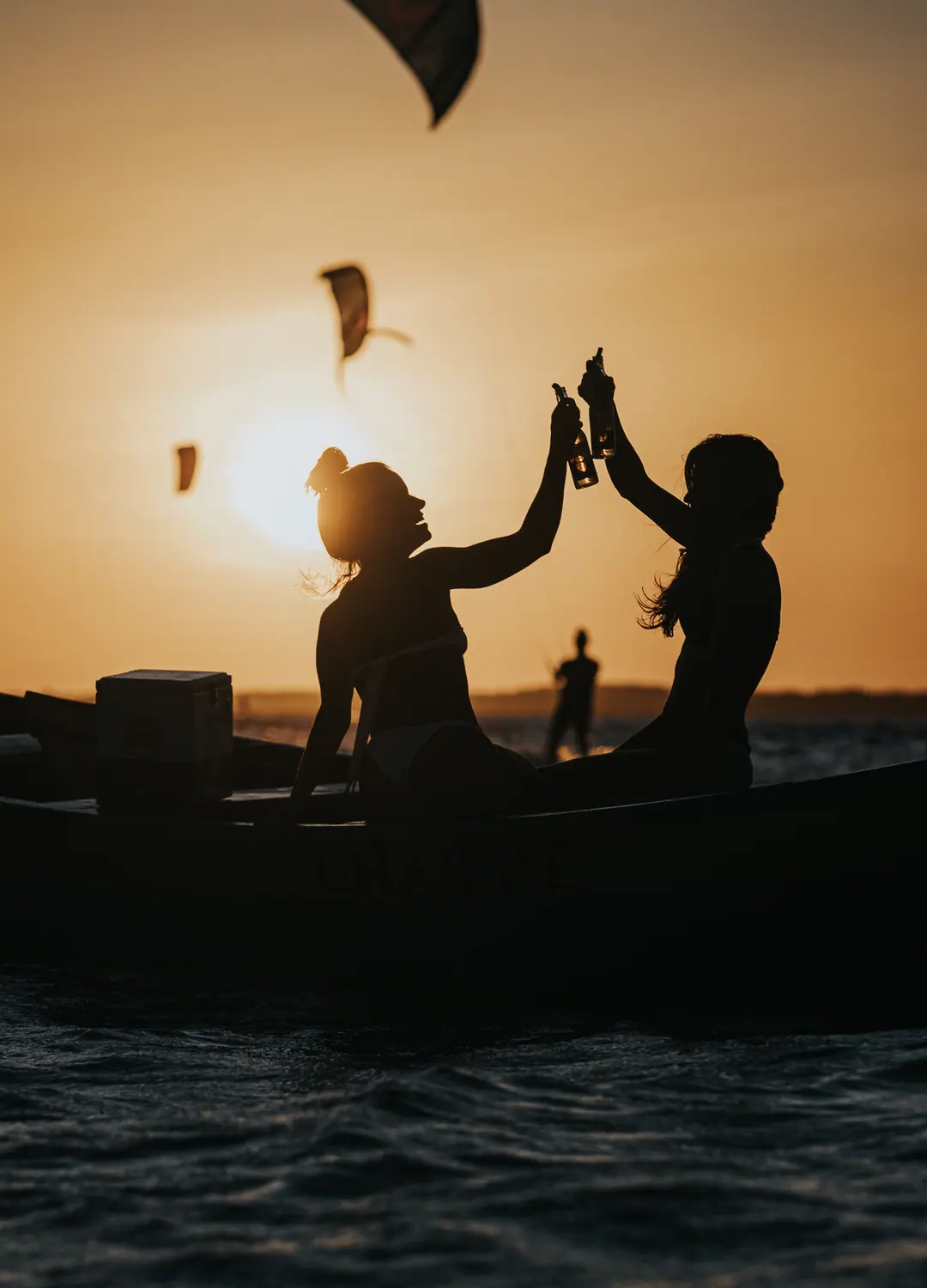 Duas pessoas brindando num barco ao pôr do sol