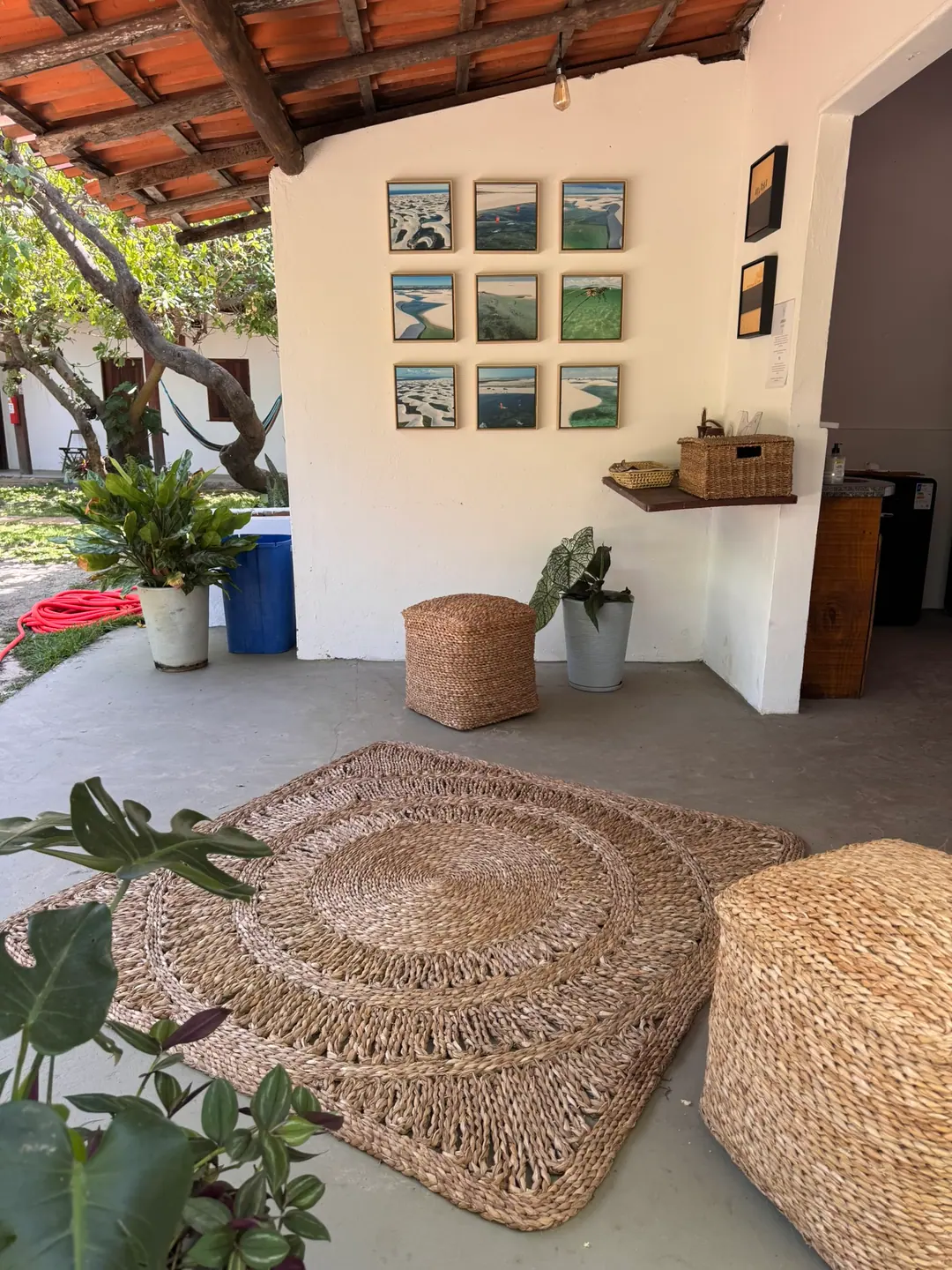 Um canto da pousada, com quadros na parede e pufes